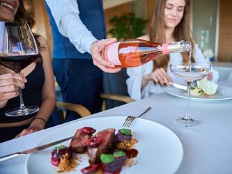 female friends eat lunch in upscale restaurant while sparkling wine is poured